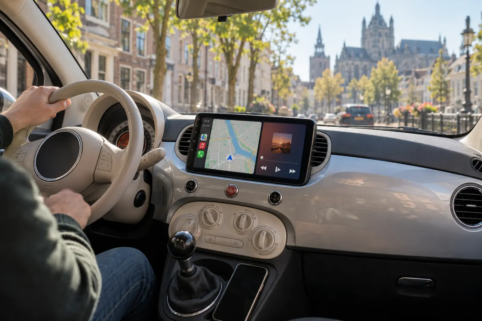 CarPlay bestellen in 's-Hertogenbosch: CarPlay-scherm met navigatie en muziek in het dashboard van een Fiat 500, met de Bossche binnenstad door de voorruit